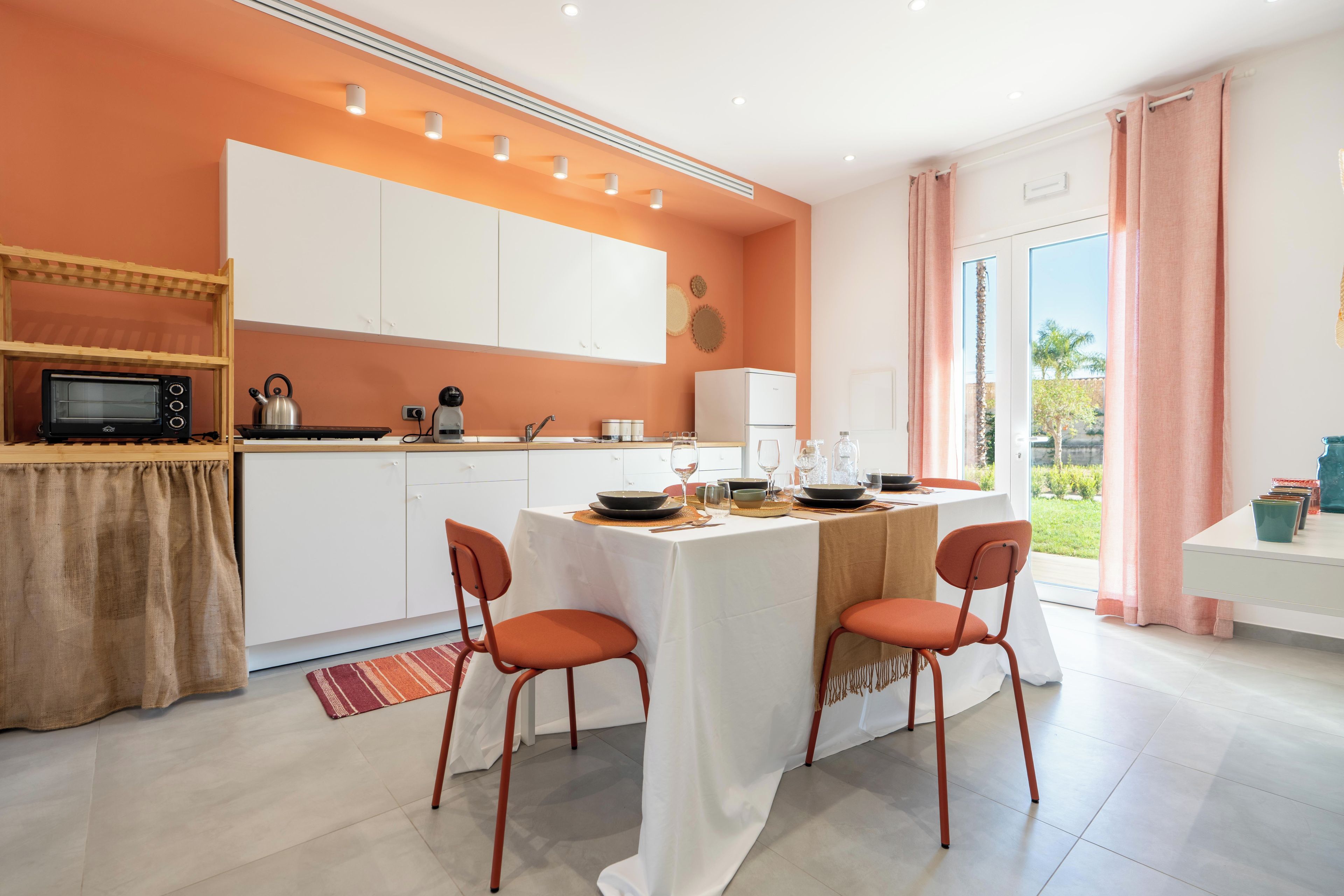 A modern kitchen with white cabinets, a built-in microwave, and a dining area with a table set for two.