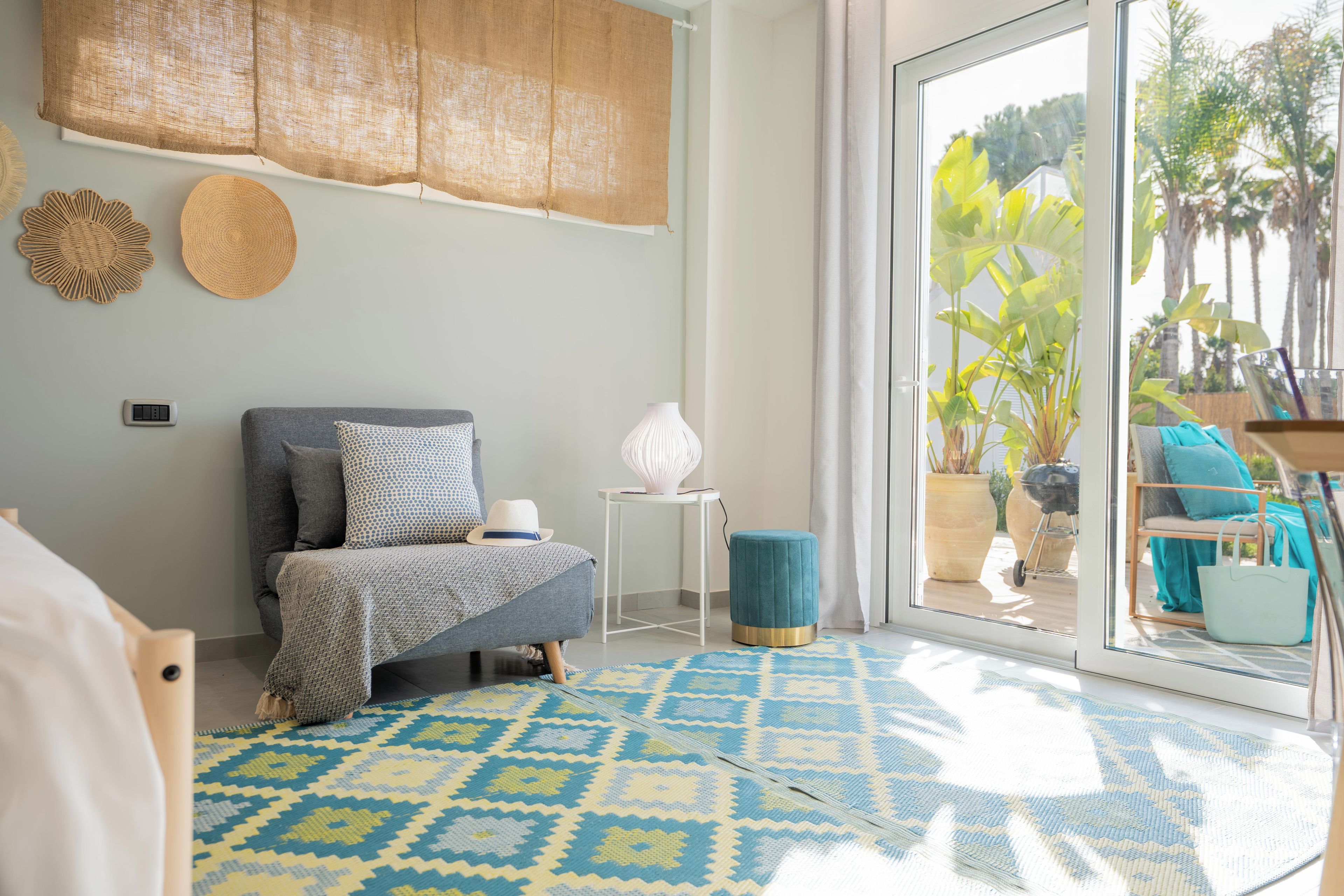 Une chambre à coucher avec un lit, une petite table, une lampe et une vue sur l’extérieur grâce à une porte-fenêtre coulissante.