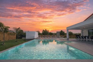 A modern outdoor pool area with clear water, surrounded by a well-maintained lawn and a wooden fence. - Villa Giaira Sicilymyhome (Ispica)
