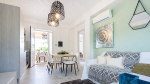 Un salon moderne comprenant un coin repas, un ensemble de canapés, un tapis à motifs et une œuvre d’art murale originale.