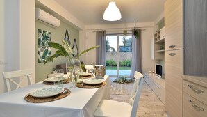 Un coin repas avec une table dressée pour quatre personnes, une cuisine dotée de meubles en bois et une vue sur l’extérieur.