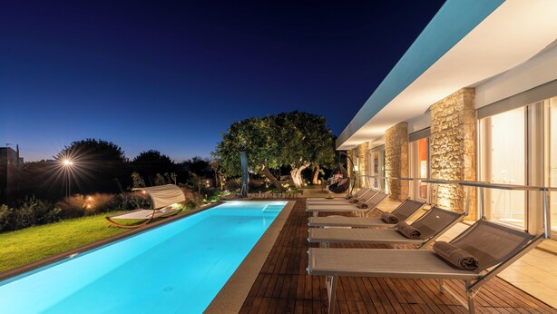 Une piscine avec des chaises longues et un mur en pierre.