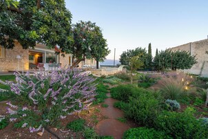 Un giardino con un muro di pietra, un vialetto e un edificio con un patio.