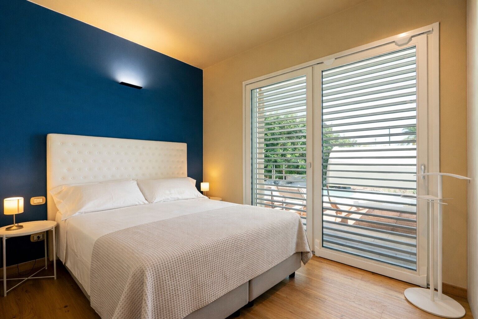 Une chambre à coucher avec un lit, des tables de chevet et une vue dégagée grâce à de grandes portes-fenêtres coulissantes.