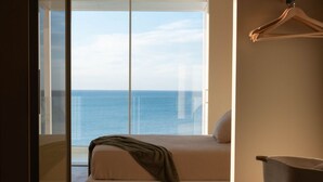 Ein Schlafzimmer mit Bett, Meerblick und einer Schiebeglasdoor.