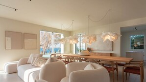 Ein modernes Interieur mit einer Couch, einem Esstisch, Stühlen und einem großen Fenster mit Blick.