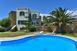 A modern two-story house with a swimming pool, stone walls, and green shutters. - Tinos Luxury Two-storey Villa With Private Pool (Tinos)