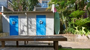 Uma mesa de piquenique de madeira em frente a um edifício com duas portas azuis, cada uma decorada com uma estrela.