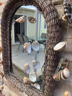 Ein Spiegel mit Korpus aus Weidengeflecht und darin aufgehängten Muscheln.