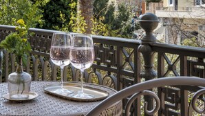 Un balcón con una mesa dispuesta para dos personas, con vistas a un paisaje montañoso.