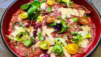 Eine Schüssel mit rohem Fleisch, Käse, Kirschtomaten und Salat.