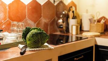 Une cuisine avec un dosseret de crédence en carreaux hexagonaux, une planche à découper avec un chou, un couteau et un bocal en verre.
