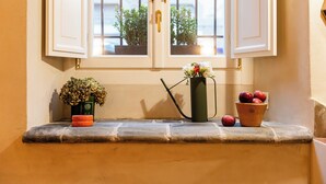 A window with white shutters, a potted plant, a watering can, and a terracotta pot with apples. - Charming apartment in Rome a stone's throw from Villa Ada and Villa Borghese (Roma)