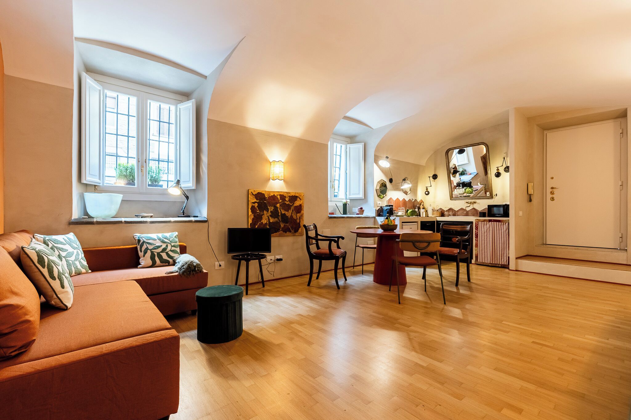Un salon moderne comprenant un canapé, un téléviseur et un coin repas avec des chaises et une table.