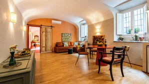 A spacious living area with a wooden floor, a dining table with chairs, a sofa set, and a kitchen area with a window. - Charming apartment in Rome a stone's throw from Villa Ada and Villa Borghese (Roma)