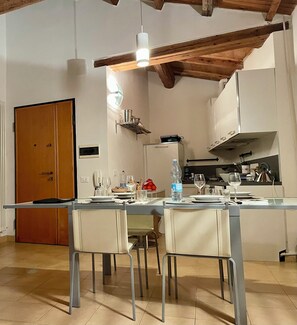 Un espace repas avec une longue table, des chaises et une cuisine en arrière-plan.