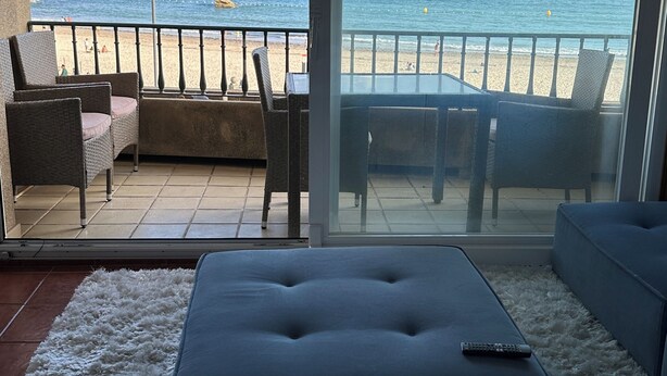 A balcony with a view of the sea and beach, furnished with wicker chairs and a table. - Unbeatable location, first line of the beach in the middle of Silgar promenade. (sanxenxo)