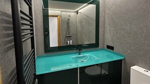 A modern bathroom with a glass sink, a large mirror, and a toilet. - Unbeatable location, first line of the beach in the middle of Silgar promenade. (sanxenxo)