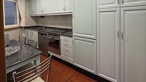 A kitchen with white cabinets, a granite countertop, and a stainless steel range hood. - Unbeatable location, first line of the beach in the middle of Silgar promenade. (sanxenxo)