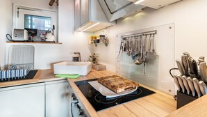 A modern kitchen with a built-in oven, a cutting board on the countertop, and a knife block. - Apartment “Auszeitwohnung Sasbachwalden - Pool” with Shared Terrace, Balcony, Sauna & Wi-Fi (Sasbachwalden)