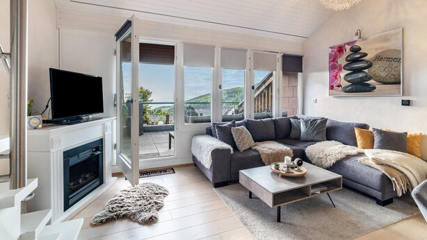 A modern living room with a fireplace, a sofa, a coffee table, and a television. - Apartment “Auszeitwohnung Sasbachwalden - Pool” with Shared Terrace, Balcony, Sauna & Wi-Fi (Sasbachwalden)