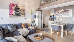 A modern living room with a sofa, coffee table, and dining area. - Apartment “Auszeitwohnung Sasbachwalden - Pool” with Shared Terrace, Balcony, Sauna & Wi-Fi (Sasbachwalden)
