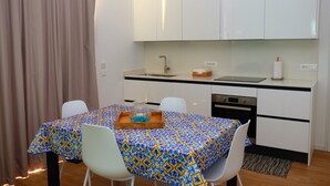 Eine kleine Küche mit weißen Schränken, einer Spüle und einem Essbereich mit Tisch und Stühlen.