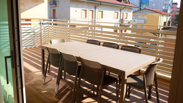 Ein Balkon mit Tisch und Stühlen, Blick auf Gebäude und einer Tür.