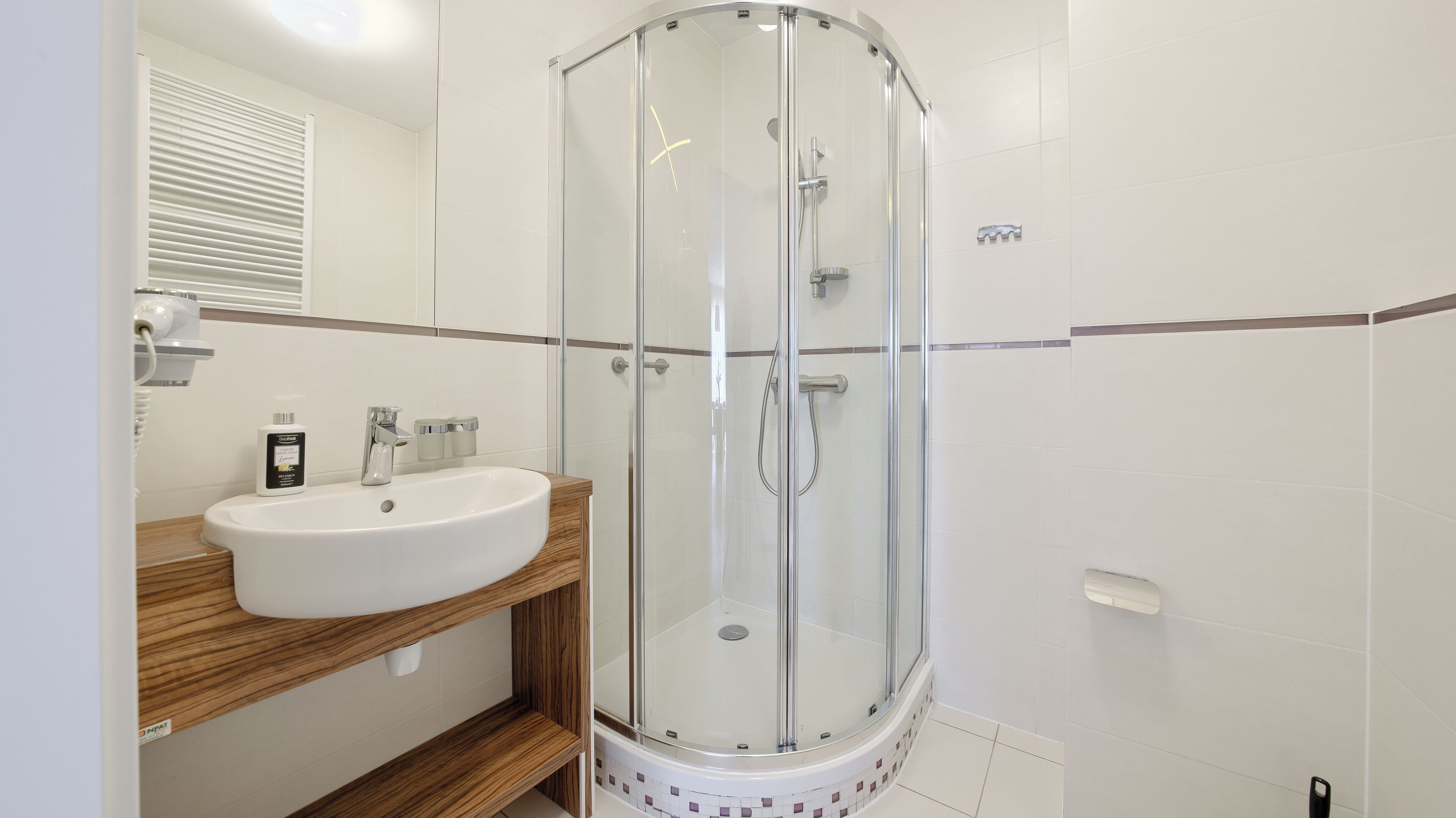 A modern bathroom with a glass-enclosed shower, a white sink, and wooden shelves.