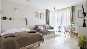 A modern hotel room with a bed, a sofa, a dining area, and a desk. - Apartamenty Sun & Snow Baltic Cliff (Niechorze)