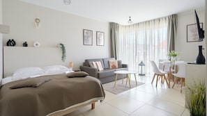 Une chambre d’hôtel moderne équipée d’un lit, d’un canapé, d’un coin repas et d’un bureau.