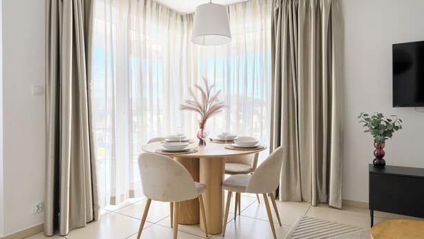 A dining area with a round table, chairs, and a vase with dried plants. - Apartamenty Sun & Snow Baltic Cliff (Niechorze)