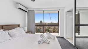 Habitación de hotel moderna con una cama grande, vista a la ciudad y equipo de aire acondicionado.