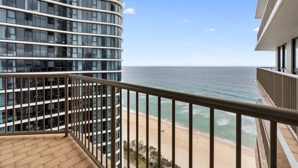 Un edificio moderno con fachada curva que da a una playa.