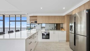 Una cocina moderna con una isla grande, electrodomésticos de acero inoxidable y vistas al exterior.