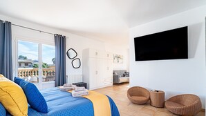 Een slaapkamer met een bed, een televisie en een balkon.