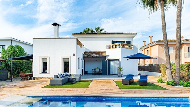 Een modern huis met een zwembad, buitenmeubels en een patio.