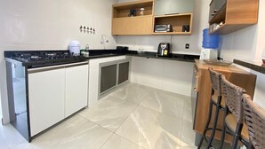 A modern kitchen with a central island, built-in cabinets, and a bar area with stools. - Teresa's House - Beach and Comfort (Cabo Frio)