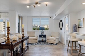 A living room with a sofa, armchairs, a coffee table, and a rug. There are windows with blinds, a lamp, and a vase on a side table. - Vanderbilt Landings - only steps to the Beach! (Naples)