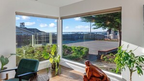 A modern room with large windows, a green chair, and a small table. - Ocean Breeze-Charming, 3 bedroom 2 bath home in old town Bodega Bay (Bodega Bay)