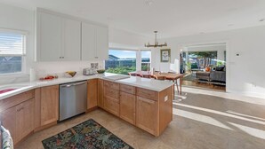 A modern kitchen with white cabinets, a dishwasher, and a dining area with a view. - Ocean Breeze-Charming, 3 bedroom 2 bath home in old town Bodega Bay (Bodega Bay)