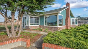 A single-story house with a brick chimney, large windows, and a well-maintained garden. - Ocean Breeze-Charming, 3 bedroom 2 bath home in old town Bodega Bay (Bodega Bay)
