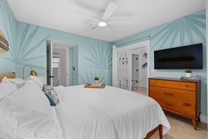 A bedroom with a bed, a dresser, a TV, and a ceiling fan. - 2 homes • 2 Heated Pools • 2 Courts • Sleeps 18 (Jacksonville Beach)