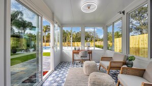 A sunroom with large windows, a ceiling fan, a wooden table with chairs, and a patterned floor. - 2 homes • 2 Pools • 2 Courts • Sleeps 18 (Jacksonville Beach)