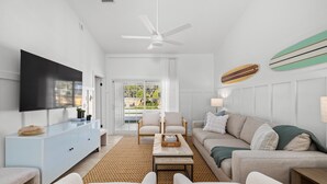A modern living room with a flat-screen TV, two sofas, a coffee table, and a ceiling fan. - 2 homes • 2 Pools • 2 Courts • Sleeps 18 (Jacksonville Beach)