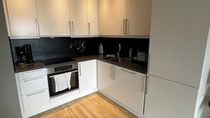 A modern kitchen with white cabinets, a black countertop, and a stainless steel oven. - Apartment in a quiet area at Lade (Trøndelag)