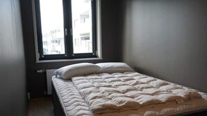 A small, dimly lit room with a single bed, a window, and a radiator. - Apartment in a quiet area at Lade (Trøndelag)