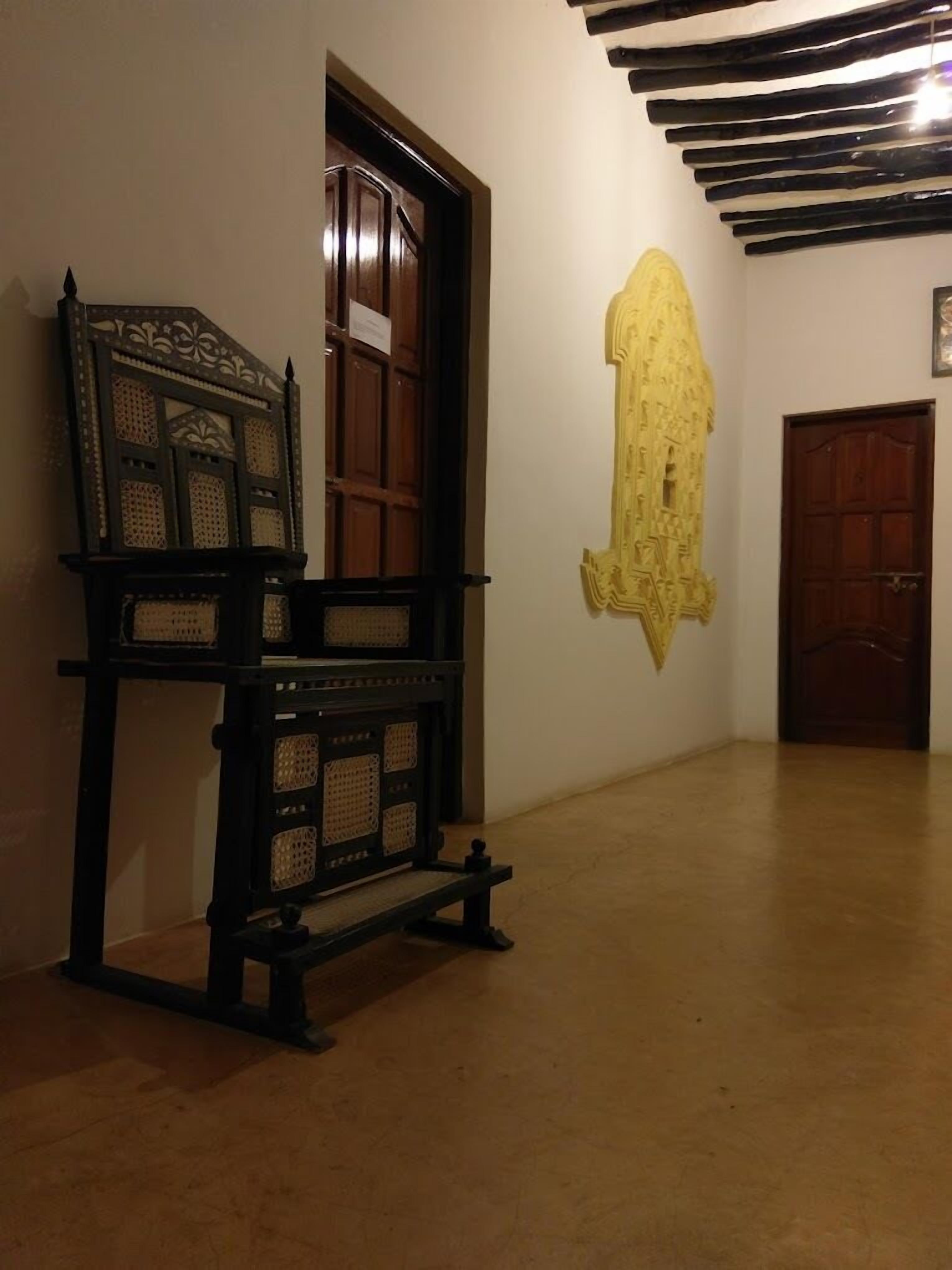 Une pièce dotée d’une porte en bois traditionnelle, d’un banc orné de sculptures complexes et d’un grand élément décoratif mural.