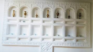 A wall with a decorative shelf unit featuring multiple compartments, some with vases and others empty.