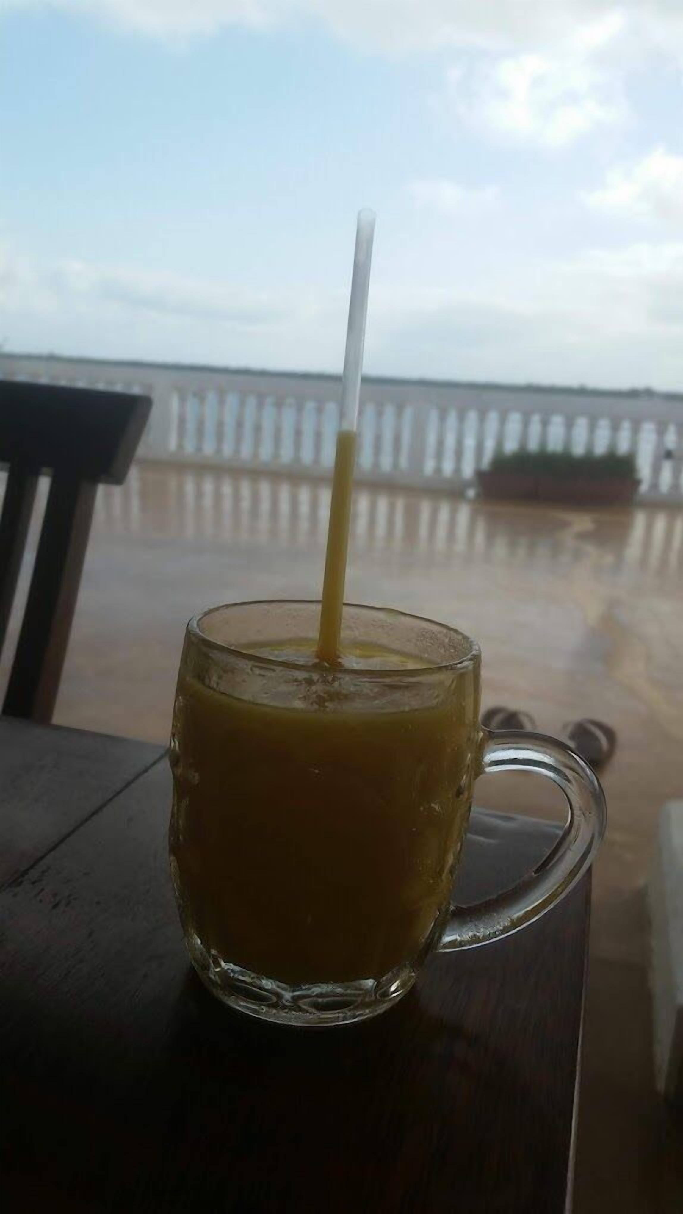 A glass mug with a straw on a wooden table.